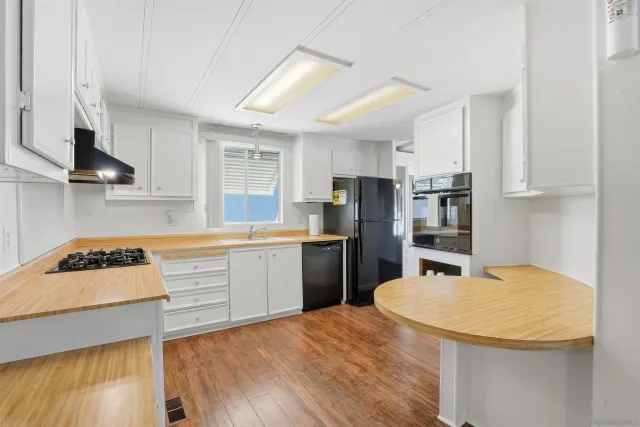 a kitchen with refrigerator a stove a sink cabinets and wooden floor