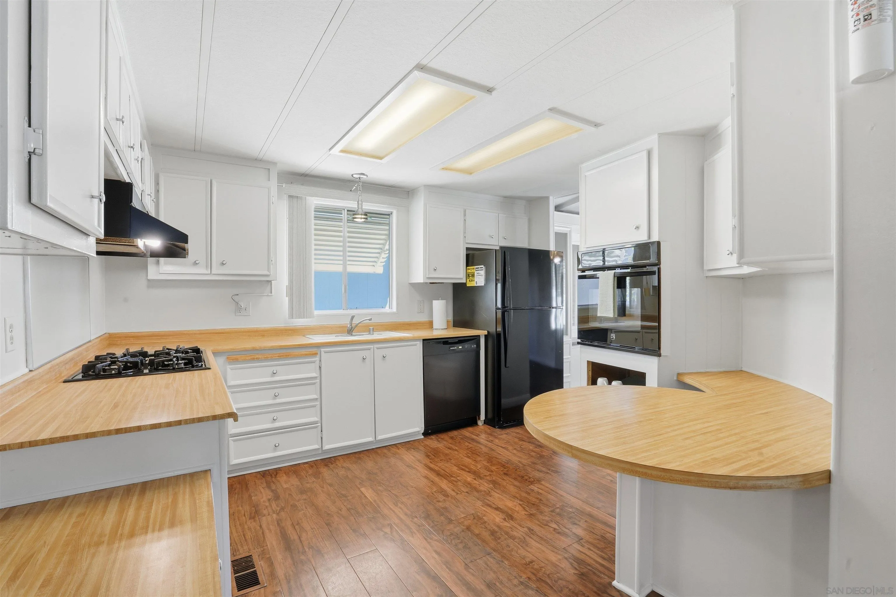 9255 North Magnolia Avenue, Unit 339 Santee, CA 92071 - Photo 4 of 55 a kitchen with refrigerator a stove a sink cabinets and wooden floor