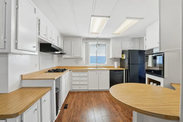 a kitchen with a sink a stove a refrigerator cabinets and a wooden floor