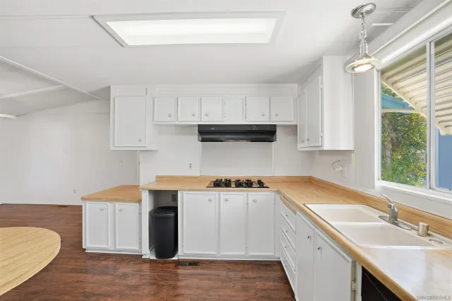 a kitchen with stainless steel appliances granite countertop a sink stove and white cabinets with wooden floor