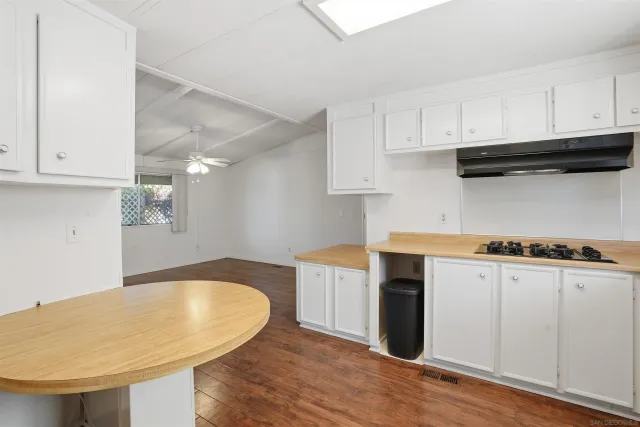 a kitchen with stainless steel appliances granite countertop a sink dishwasher a stove and white cabinets with wooden floor