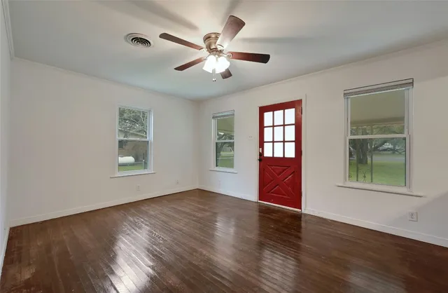 a view of an empty room with wooden floor and a window