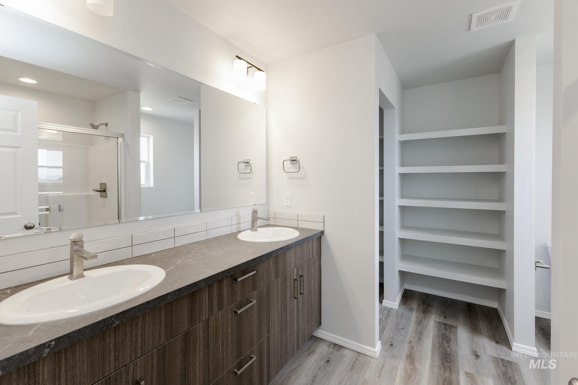 10833 Rutland Street Caldwell, ID 83605 - Photo 23 of 26 Full bathroom with a stall shower, double vanity, and light wood-style flooring