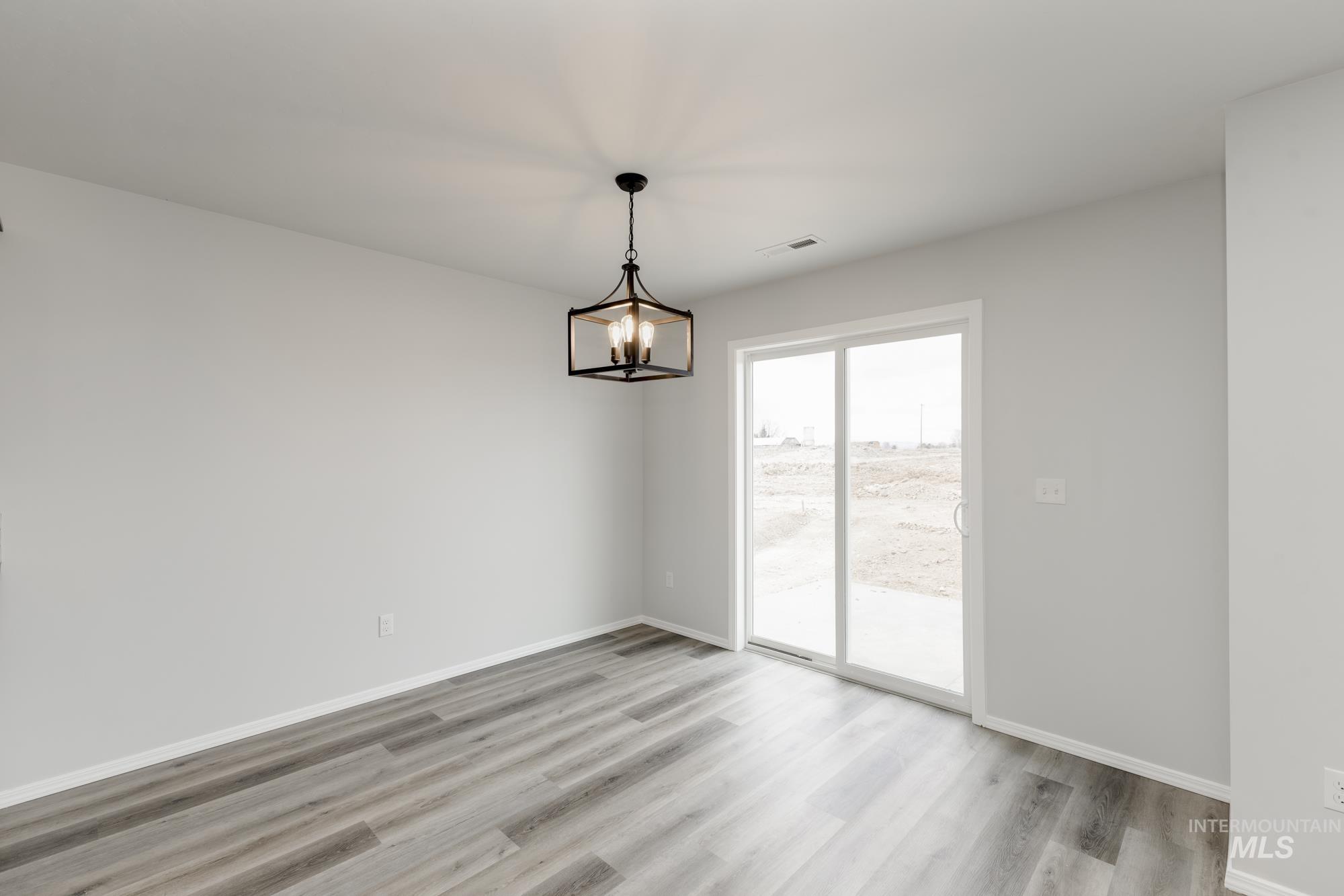 10833 Rutland Street Caldwell, ID 83605 - Photo 6 of 26 Spare room with light wood-style flooring and a chandelier