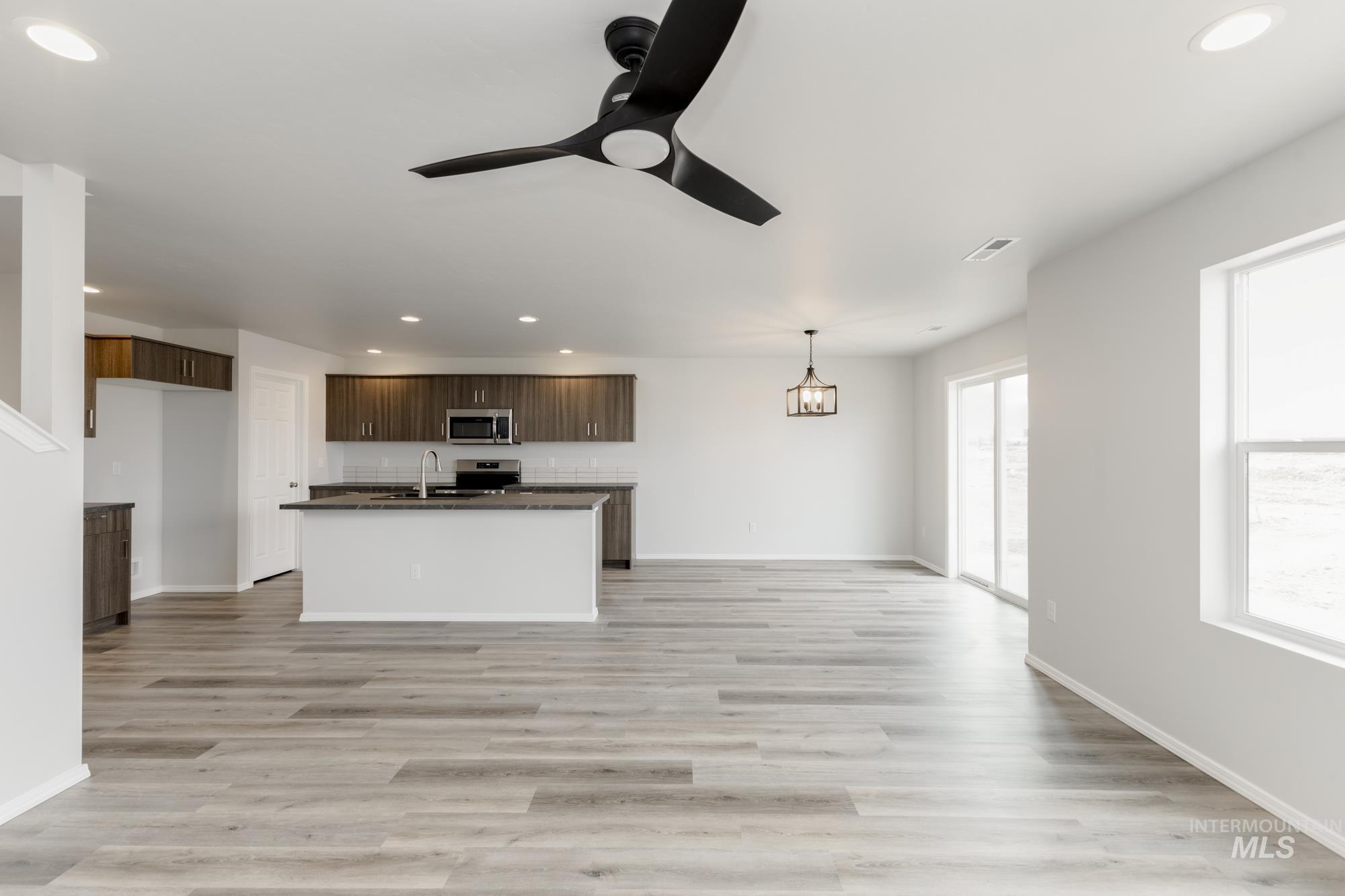 10833 Rutland Street Caldwell, ID 83605 - Photo 26 of 26 Kitchen with recessed lighting, open floor plan, dark brown cabinetry, a kitchen island with sink, and light wood-style flooring