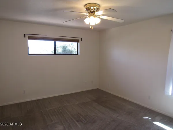 an empty room with a window and a fan