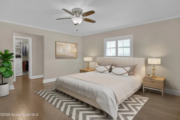 a view of an empty room with wooden floor and a ceiling fan