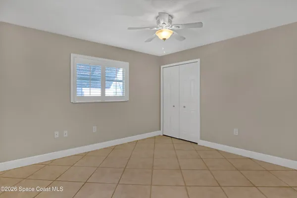 a view of an empty room with window and chandelier fan