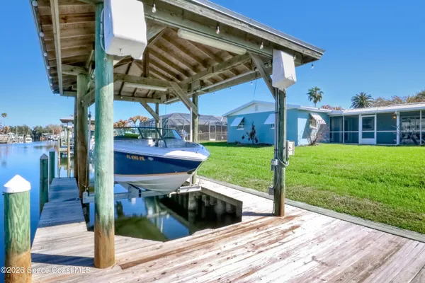 a backyard of a house with table and chairs under an umbrella