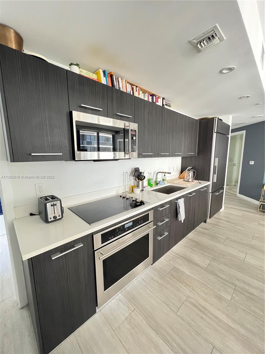 45 Southwest 9th Street, Unit 1908 Miami, FL 33130 - Photo 23 of 51 a kitchen with stainless steel appliances kitchen island a sink stove and cabinets