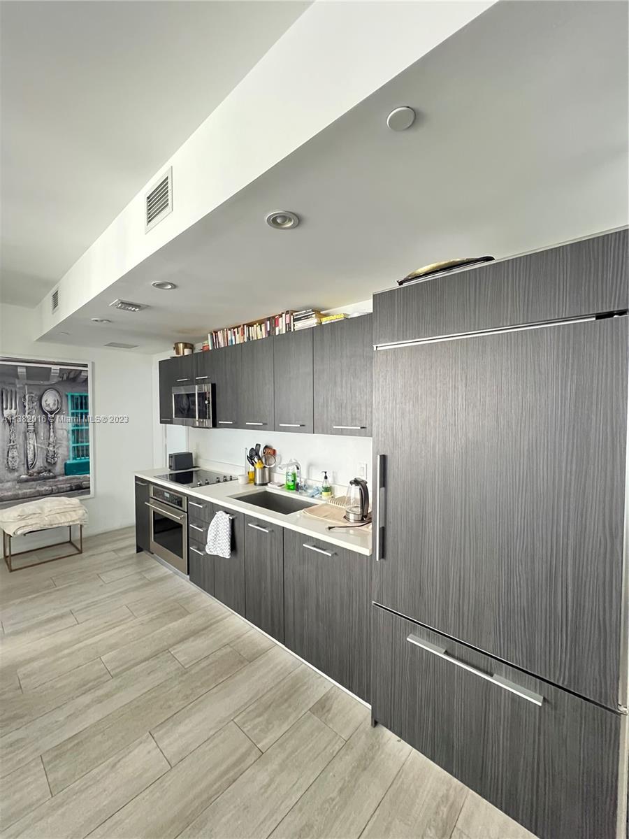 45 Southwest 9th Street, Unit 1908 Miami, FL 33130 - Photo 27 of 51 a kitchen with stainless steel appliances granite countertop a refrigerator a sink dishwasher a stove and white countertops with wooden floor