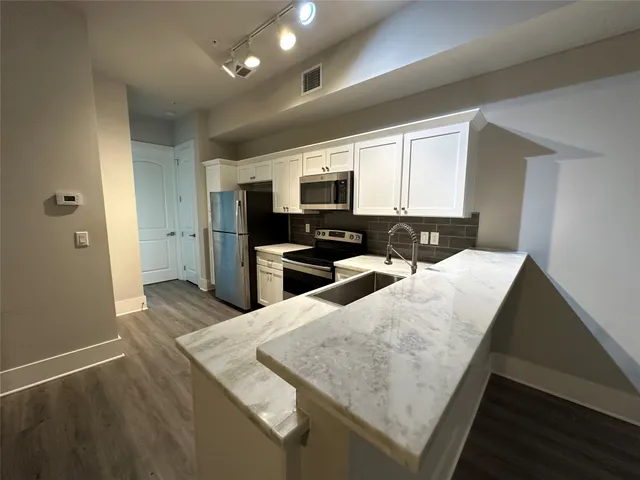 a large kitchen with a center island and stainless steel appliances