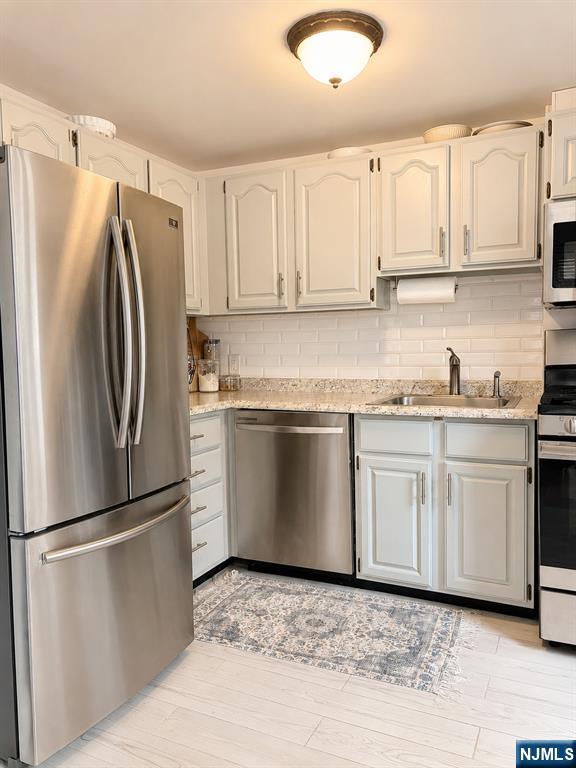 100 Prospect Avenue, Unit 5H Hackensack, NJ 07601 - Photo 10 of 17 a kitchen with granite countertop a refrigerator sink and white cabinets