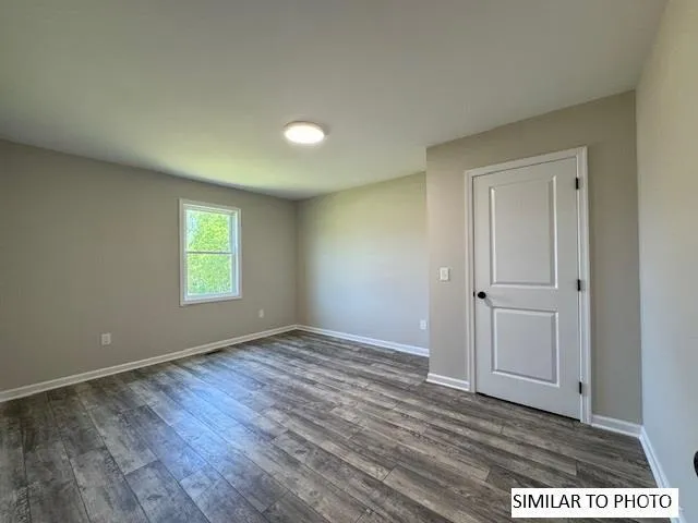 an empty room with wooden floor and window