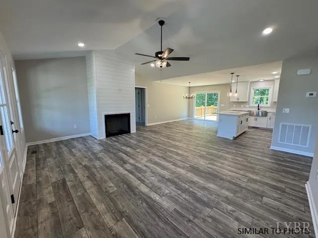 an empty room with wooden floor ceiling fan and windows
