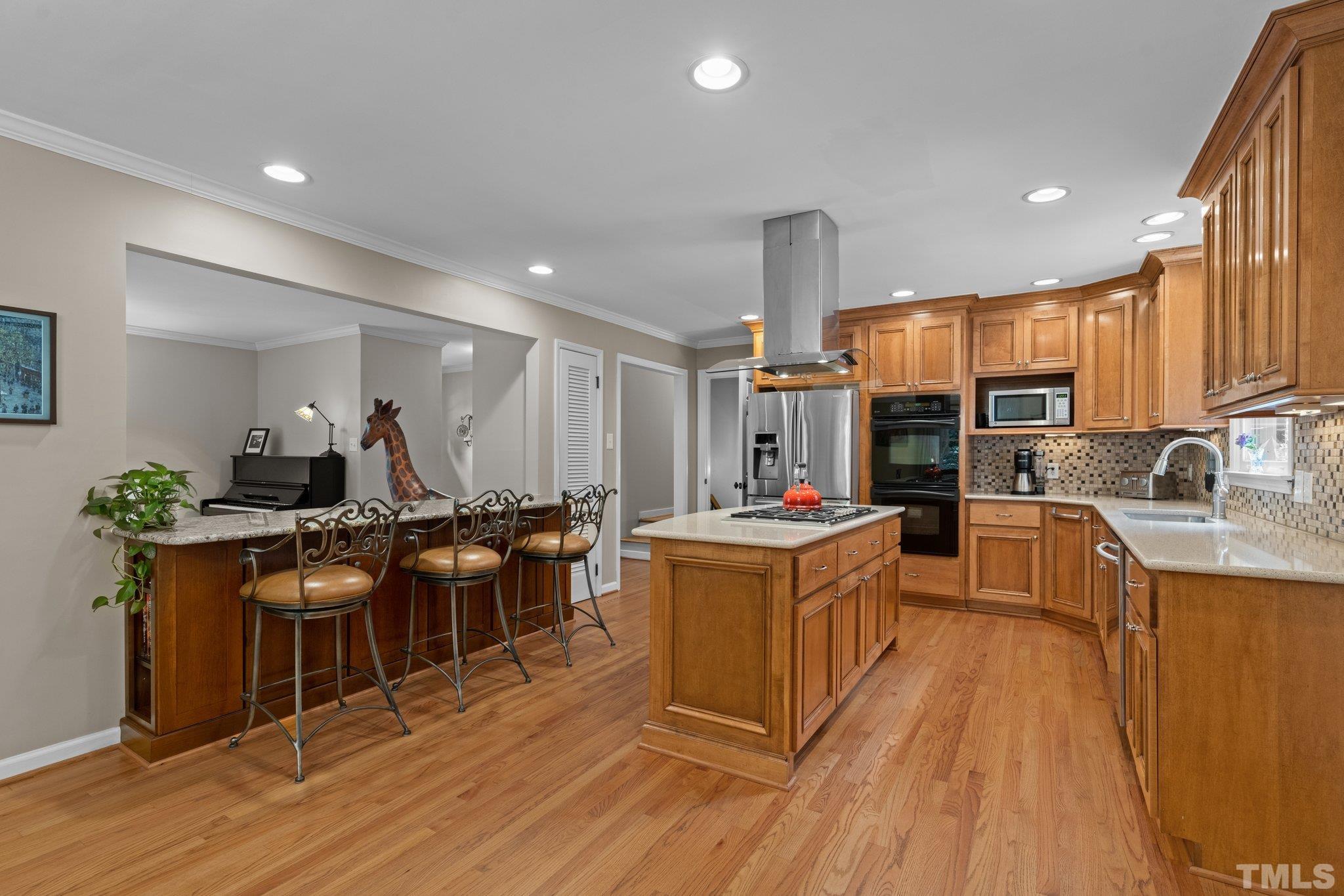 4116 Spruce Drive Raleigh, NC 27612 - Photo 12 of 51 a kitchen with stainless steel appliances kitchen island granite countertop wooden floors and wooden cabinets