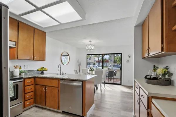 a kitchen with stainless steel appliances granite countertop a sink dishwasher cabinets with a dining table and chairs