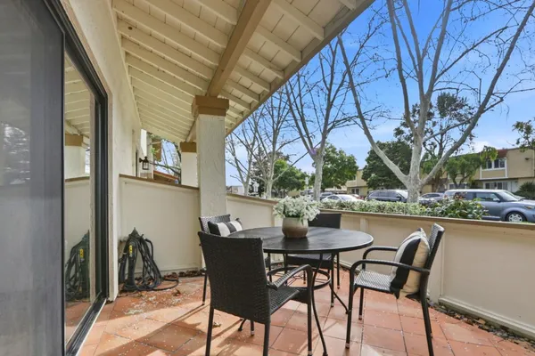 a patio with table and chairs and potted plants