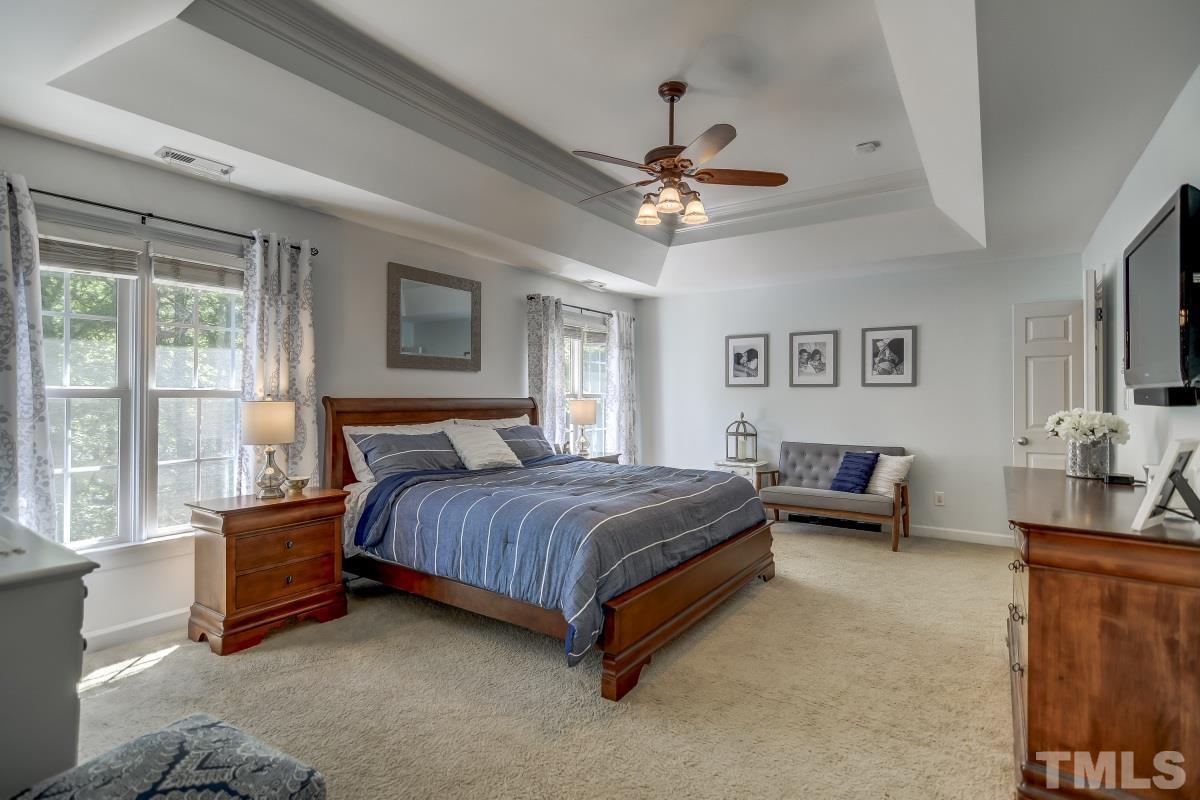 8401 Wapello Lane Raleigh, NC 27613 - Photo 14 of 26 a spacious bedroom with a bed a chandelier and a large window