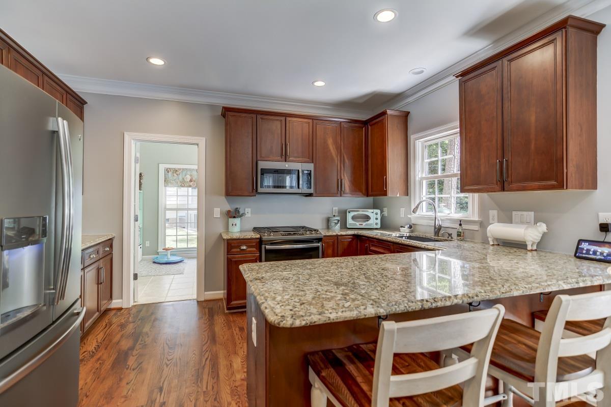 8401 Wapello Lane Raleigh, NC 27613 - Photo 9 of 26 a kitchen with granite countertop a stove a sink dishwasher a refrigerator cabinets and wooden floor
