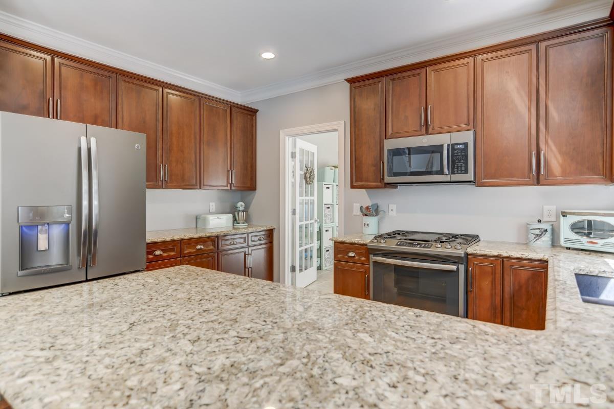 8401 Wapello Lane Raleigh, NC 27613 - Photo 10 of 26 a kitchen with stainless steel appliances granite countertop a refrigerator stove top oven and sink