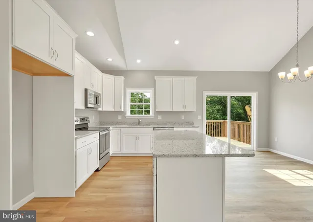 a kitchen with a sink dishwasher and white cabinets with wooden floor