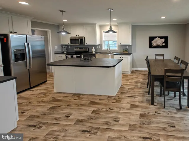 a large kitchen with stainless steel appliances kitchen island granite countertop a sink a stove a dining table and chairs