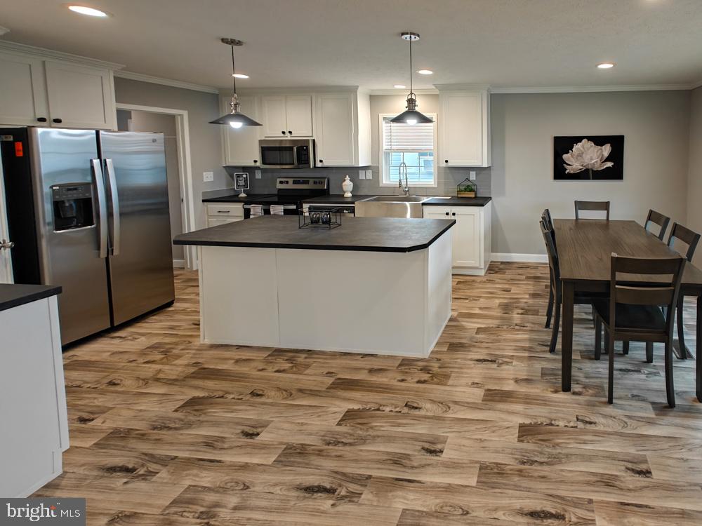 12623 Shell Mill Road, Unit 67 Bishopville, MD 21813 - Photo 4 of 22 a large kitchen with stainless steel appliances kitchen island granite countertop a sink a stove a dining table and chairs