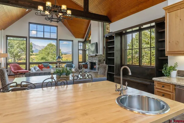 a kitchen with a sink a counter top space and living room next to a large window