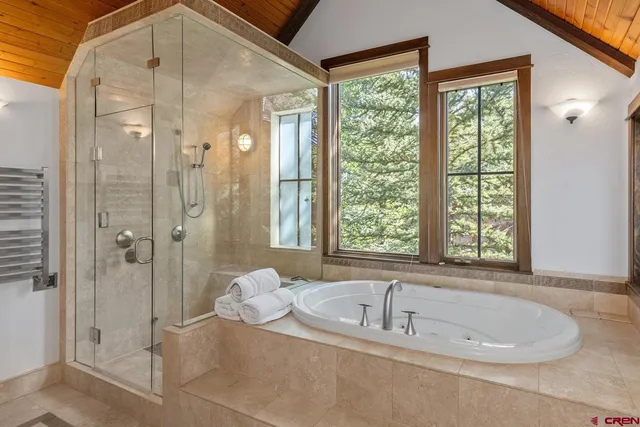 a spacious bathroom with a tub shower and windows