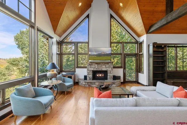 a living room with furniture a fireplace and floor to ceiling windows