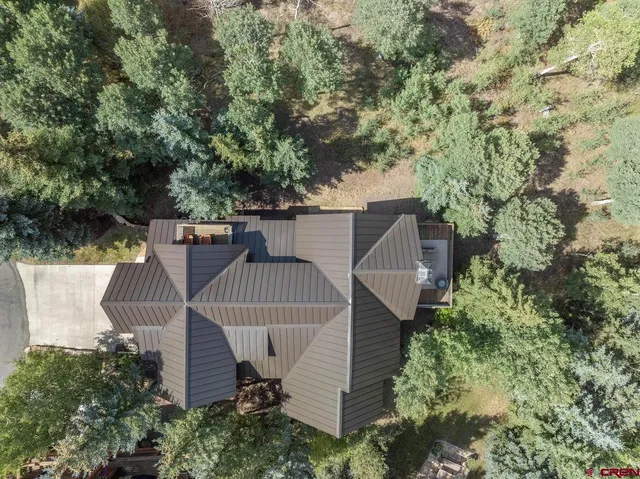 an aerial view of a house with swimming pool and large trees