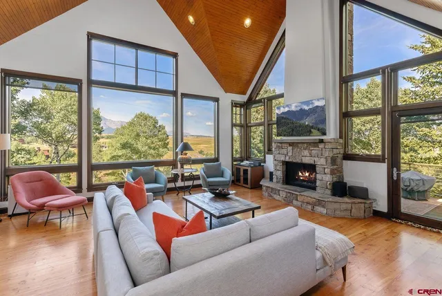 a living room with furniture a fireplace and floor to ceiling windows