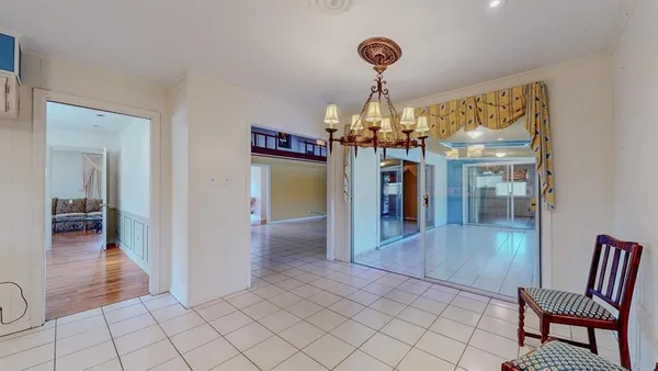 a view of a hallway to dining room and chandelier