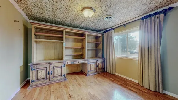 an empty room with wooden floor closet and windows