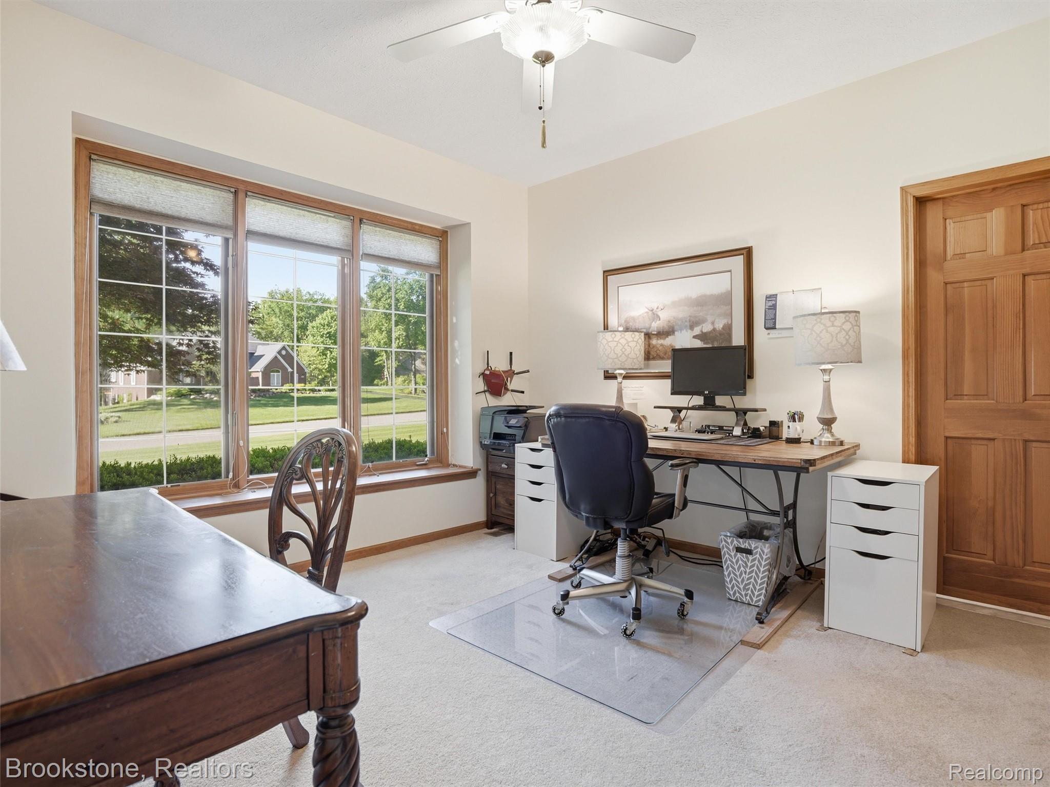 9523 Quail Ridge Run Brighton, MI 48114 - Photo 28 of 50 Light-filled room featuring a broad bay window with wood trim, neutral wall color, and a ceiling fan with integrated lighting