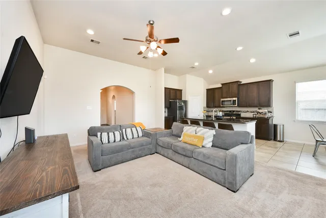 a living room with furniture kitchen view and a flat screen tv