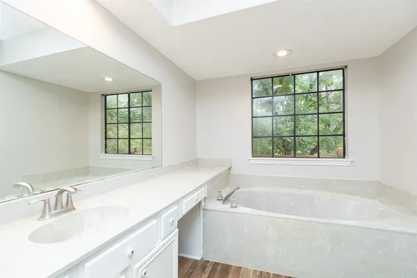 a bathroom with a granite countertop bathtub a sink and a window