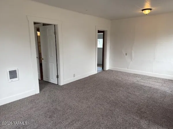 an empty room with window in back and closet area