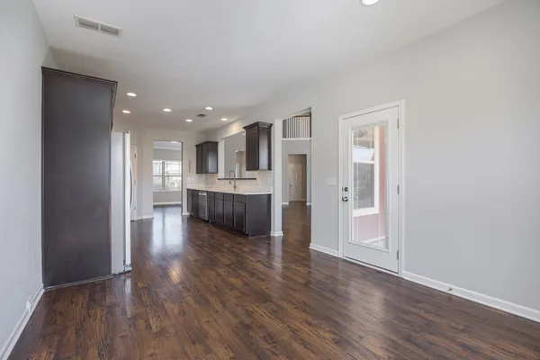 a view of an empty room with wooden floor and a bathroom