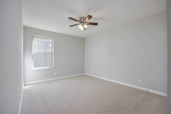 an empty room with a fan & a ceiling fan