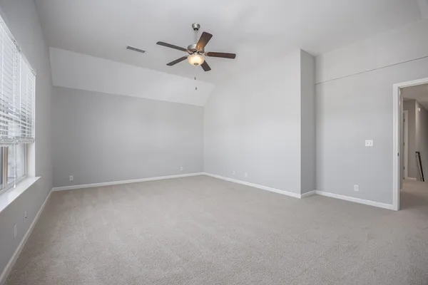 an empty room with ceiling fan and windows