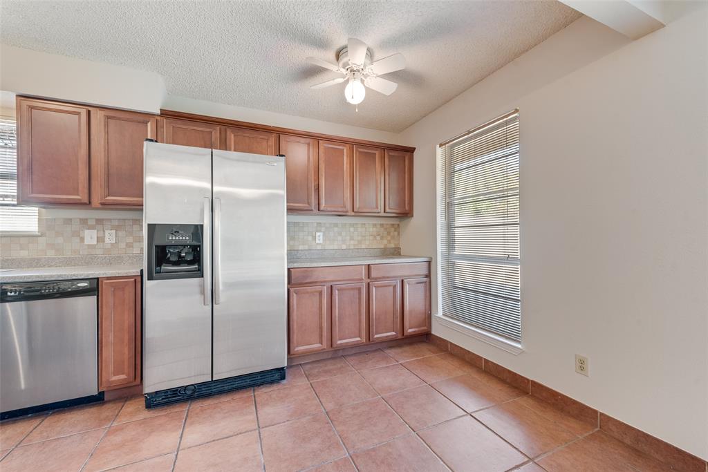 703 Rolling Ridge Lane Duncanville, TX 75116 - Photo 12 of 38 Kitchen with stainless steel appliances, light countertops, light tile patterned flooring, decorative backsplash, and brown cabinetry