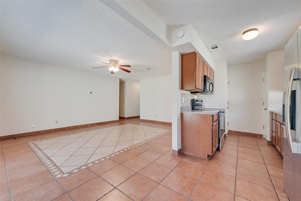 703 Rolling Ridge Lane Duncanville, TX 75116 - Photo 13 of 38 Kitchen with light tile patterned floors, appliances with stainless steel finishes, light countertops, a ceiling fan, and brown cabinets