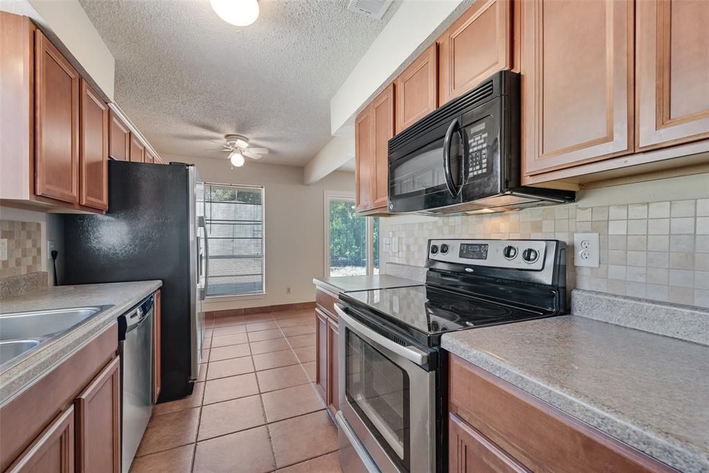 703 Rolling Ridge Lane Duncanville, TX 75116 - Photo 14 of 38 Kitchen featuring tasteful backsplash, stainless steel appliances, light tile patterned floors, light countertops, and a textured ceiling
