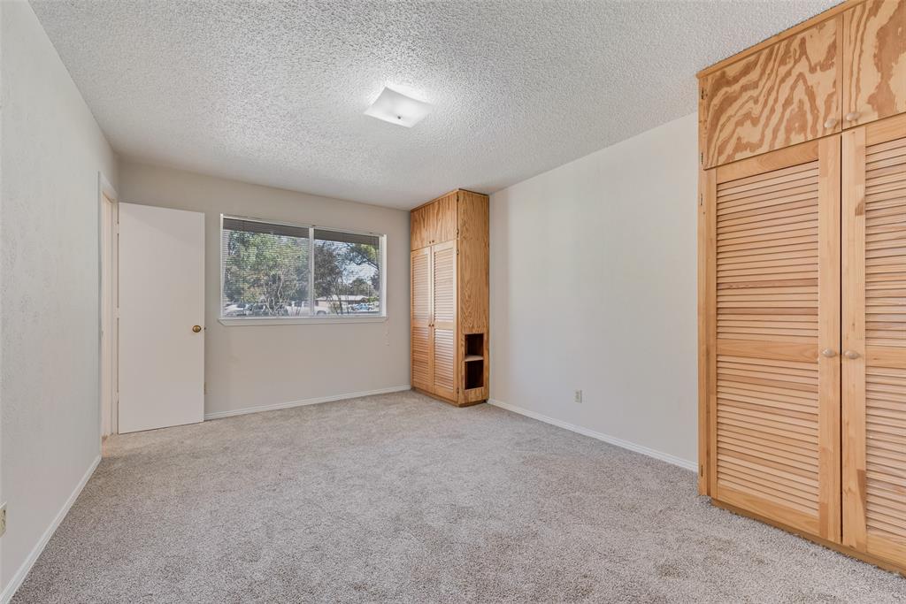 703 Rolling Ridge Lane Duncanville, TX 75116 - Photo 19 of 38 Unfurnished bedroom featuring light carpet, a textured ceiling, and multiple closets