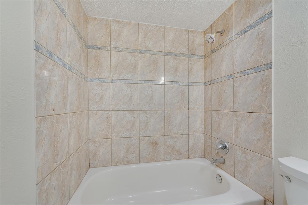 703 Rolling Ridge Lane Duncanville, TX 75116 - Photo 23 of 38 Bathroom with tub / shower combination, a textured ceiling, and a textured wall