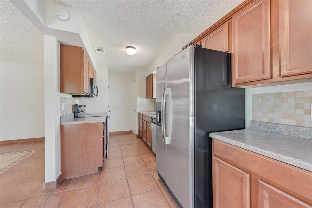 703 Rolling Ridge Lane Duncanville, TX 75116 - Photo 29 of 38 Kitchen with decorative backsplash, light tile patterned floors, stainless steel appliances, light countertops, and a textured ceiling