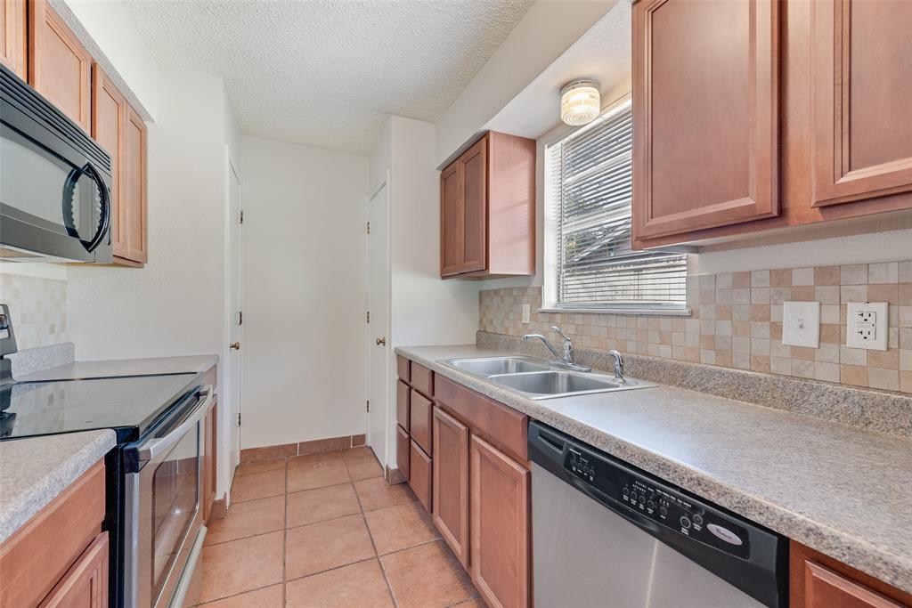 703 Rolling Ridge Lane Duncanville, TX 75116 - Photo 30 of 38 Kitchen featuring stainless steel appliances, tasteful backsplash, a textured ceiling, light tile patterned flooring, and light countertops
