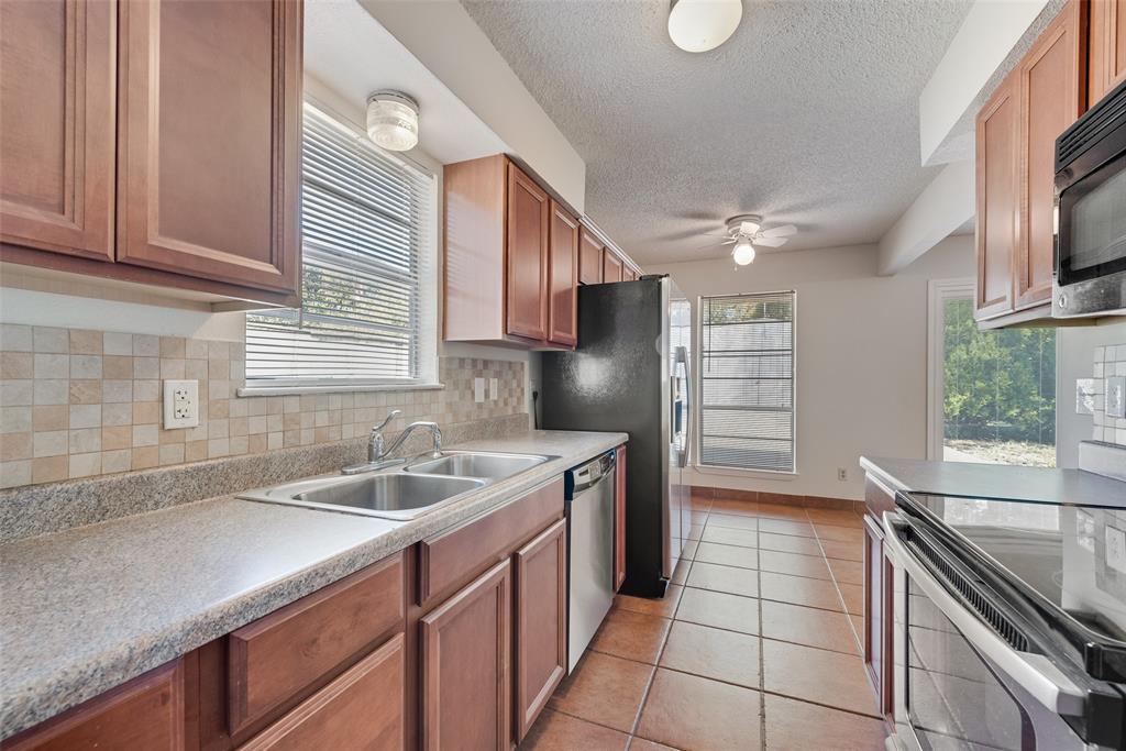 703 Rolling Ridge Lane Duncanville, TX 75116 - Photo 34 of 38 Kitchen featuring appliances with stainless steel finishes, decorative backsplash, light tile patterned flooring, light countertops, and a textured ceiling